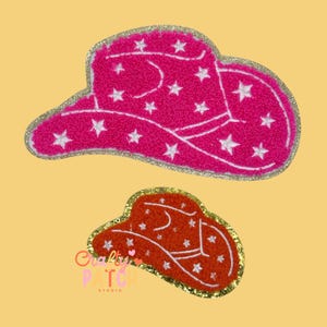May include: Two cowboy hat patches. The larger patch is hot pink with white star and line details, and a gold glitter border. The smaller patch is orange with white star and line details, and a gold glitter border. The patches are on a yellow background.