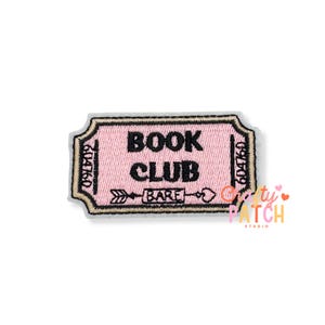 May include: A rectangular embroidered patch shaped like a ticket with a light pink background and black border. The text reads BOOK CLUB with an arrow graphic containing the word BARE. The numbers 604760 are stitched on both sides of the ticket.
