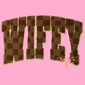 May include: Brown and tan checkered patch with the word "WIFEY" in a bold, block letter style. The patch has a gold glitter border and is set against a pink background. The patch is from Crafty Art Studio.