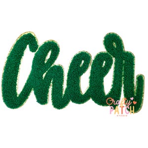 May include: Green chenille patch with the word "Cheer" in a cursive font. The edges are outlined in gold. The patch has a textured, fuzzy appearance. The "Crafty Patch Studio" logo is in the bottom right corner.