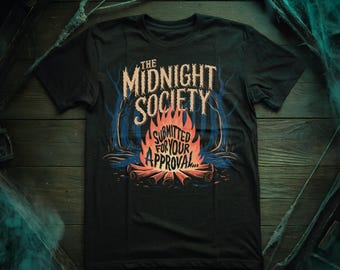 May include: Black t-shirt with a graphic of a campfire in a forest. The text "The Midnight Society" and "Submitted for your approval..." is printed on the shirt.