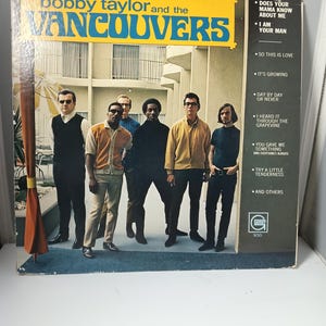 May include: A vintage vinyl record album cover featuring the band Bobby Taylor and the Vancouvers. The album cover has a yellow and blue banner with the band's name. The album cover also lists song titles and the Gordy record label.