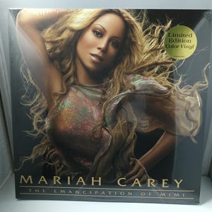 May include: A sealed vinyl record album featuring Mariah Carey. The album cover shows Mariah Carey with long, wavy blonde hair. The album title "The Emancipation of Mimi" is displayed at the bottom. A sticker indicates it is a limited edition colour vinyl.
