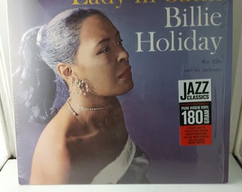 Könnte beinhalten: Ein Vinyl-Schallplattenalbum mit dem Titel "Lady in Satin" von Billie Holiday. Das Albumcover zeigt ein Porträt von Billie Holiday im Profil. Das Album ist ein Jazz Classics 180 Gramm reines Vinyl, Stereo.