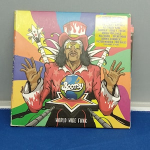 May include: A square vinyl record jacket featuring a colorful illustration of a figure in a red hat and star-shaped sunglasses holding a globe. The text reads Bootsy, World Wide Funk, and lists various artists including Big Daddy Kane and Chuck D.