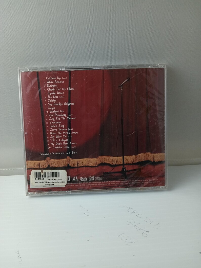 May include: A CD case with a red stage curtain design and a microphone stand. The tracklist includes songs such as "White America" and "Superman." The CD is sealed in plastic.