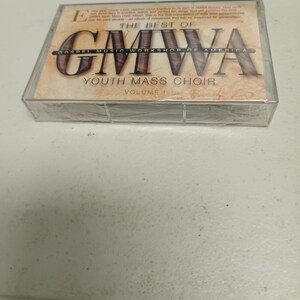 Pode incluir: Uma caixa de fita cassete selada com "The Best Of GMWOA Gospel Music Workshop Of America Youth Mass Choir Volume 1." A caixa tem um exterior de plástico transparente com um rótulo castanho.