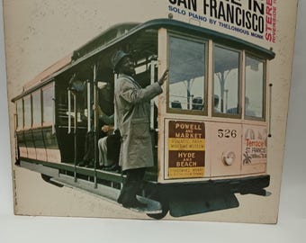 May include: Album cover for "Thelonious Alone in San Francisco" featuring a black and white image of a San Francisco cable car. The album title and artist's name are in bold black text. The cover includes the text "Solo Piano by Thelonious Monk".