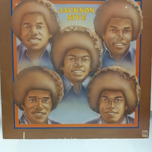 May include: Album cover for "Dancing Machine" by The Jackson 5. The cover features five portraits of the group members with large, brown afros. The album title and band name are in yellow text against a brown background.