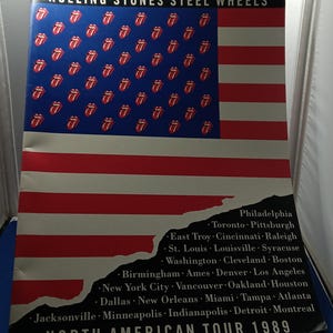 Puede incluir: Un póster de la gira norteamericana de 1989 de Rolling Stones Steel Wheels con un diseño de bandera estadounidense modificado. El campo azul contiene logotipos de lengua rojos y blancos, y la esquina inferior derecha enumera las ciudades.