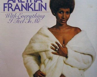 May include: A woman with an afro hairstyle wears a white fur coat and poses for a photo. The album cover features the text "Aretha Franklin" and "With Everything I Feel In Me".