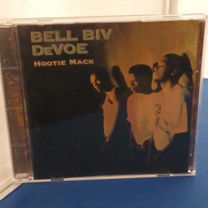 Könnte beinhalten: Eine CD-Hülle mit dem Album Hootie Mack von Bell Biv DeVoe. Das Cover zeigt den Gruppennamen und den Albumtitel in goldener Schrift vor einem dunklen Hintergrund, wobei die Silhouetten von drei Personen in warmem Licht zu sehen sind.