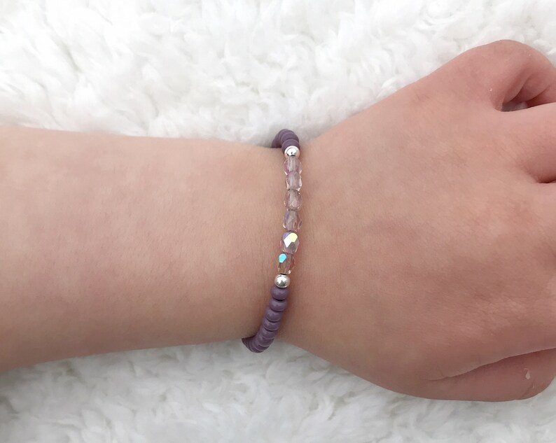 May include: A purple beaded bracelet with clear iridescent beads and silver spacers.