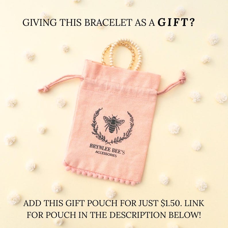 May include: A pink velvet pouch with a drawstring closure and a bee logo. The pouch is decorated with a white pom-pom trim. The text "Brynlee Bee's Accessories" is printed on the pouch.  "ADD THIS GIFT POUCH FOR JUST &pound;1.50. LINK FOR POUCH IN THE DESCRIPTION BELOW!" is written below the pouch.
