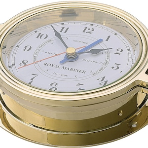 May include: A brass ship's clock with a white face and black hands. The clock has a tide indicator with a blue hand and the words "Royal Mariner" printed on the face.