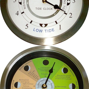 May include: A round tide clock with a silver-colored bezel. The top dial indicates high and low tide, with a second dial below for gardening by the moon phases. The clock face displays text including "Tide Clock" and "Gardening by the Moon".