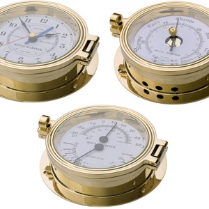 May include: Three brass nautical instruments with white faces. The instruments are a clock, a barometer, and a thermometer. The clock has black hands and Roman numerals. The barometer has a needle that points to the current barometric pressure. The thermometer has a needle that points to the current temperature in both Fahrenheit and Celsius.
