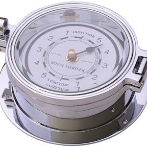 May include: A chrome-finished tide clock with a clear glass face. The clock face is white with black numerals and hands, and the text "ROYAL MARINER" is visible. The clock measures the hours until high and low tide.