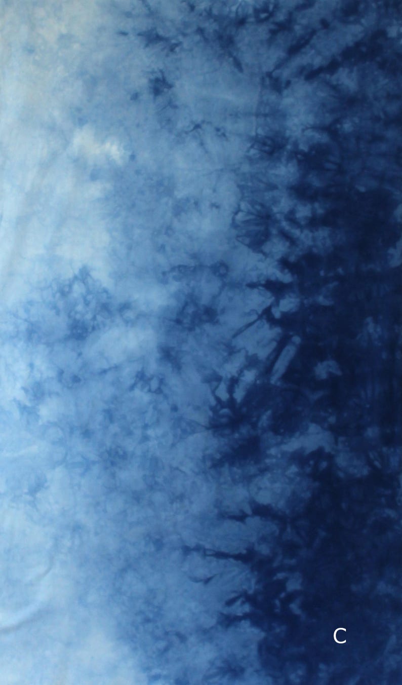 May include: A fabric featuring a tie-dye pattern with a gradient transition from light blue to deep navy blue. The design displays organic, branching, and cloud-like shapes created by the dye process. The letter C is visible in the bottom right corner.
