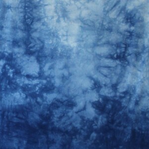 May include: A fabric textile featuring a tie-dye pattern in shades of deep navy blue and white. The design displays organic, cloud-like swirls and branching textures that transition from dark blue to light blue. The letters BB appear in white.