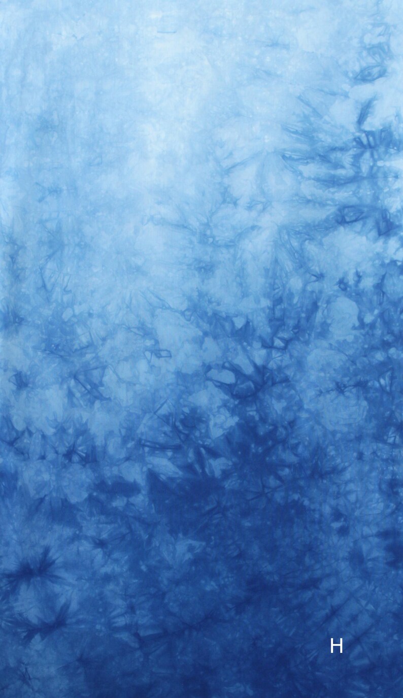 May include: Abstract tie-dye pattern in shades of blue, with a gradient effect from light to dark. The fabric has a textured appearance, with darker blue areas creating a visual depth. The letter "H" is at the bottom.