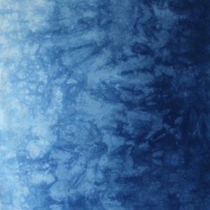May include: A fabric featuring a tie-dye pattern with a gradient effect that transitions from a light sky blue on the left to a deep navy blue on the right. The surface displays intricate, organic, and branching dark blue shapes. The letter A is visible.