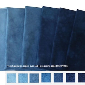 May include: Seven rectangular pieces of fabric arranged in a row, displaying a gradient of blue shades ranging from a light sky blue on the left to a deep midnight navy blue on the right. Each piece features a subtle, mottled, cloud-like texture.