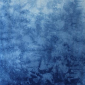 May include: A fabric textile featuring a tie-dye pattern with a gradient of blue shades, transitioning from a light sky blue at the top to a deep navy blue at the bottom. The letters AA are printed in white in the bottom right corner of the fabric.