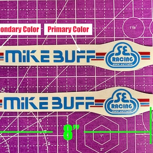 May include: Two cream-colored stickers, each approximately 8 inches long, with blue and red accents. The stickers feature the text "MIKE BUFF" and "SE RACING BMX ACTION" in blue and red, suitable for BMX enthusiasts.