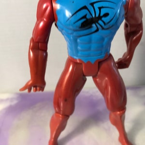 Puede incluir: Una figura de acci&oacute;n roja y azul con un dise&ntilde;o de ara&ntilde;a en el pecho. La figura tiene brazos y piernas articulados.
