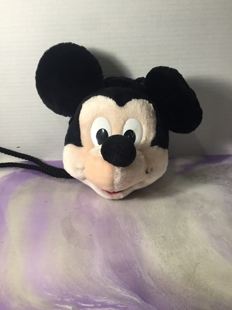 Puede incluir: Cabeza de Mickey Mouse de peluche negra y blanca con una cuerda negra atada. La cabeza es un peque&ntilde;o bolso de mano o una bolsa.