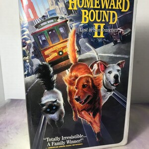 May include: A VHS tape for the Disney film "Homeward Bound II: Lost in San Francisco." The cover shows a cable car, the Golden Gate Bridge, and three animals: a cat, a golden retriever, and a white dog. The text reads "Totally Irresistible... A Family Winner!"