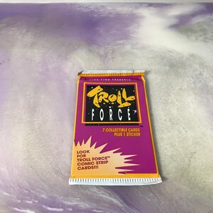 May include: A purple and yellow card pack with the text "Troll Force" and "7 collectible cards plus 1 sticker". The pack also has the text "Look for Troll Force comic strip cards!!!"