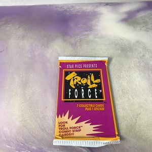 May include: A purple and yellow card pack with the text "STAR PICS PRESENTS TROLL FORCE" and "7 COLLECTIBLE CARDS PLUS 1 STICKER". The pack also has the text "LOOK FOR TROLL FORCE™ COMIC STRIP CARDS!!!"