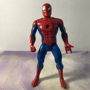 May include: A red and blue action figure of Spider-Man with a web design on his suit. The figure has a large red spider symbol on its chest.