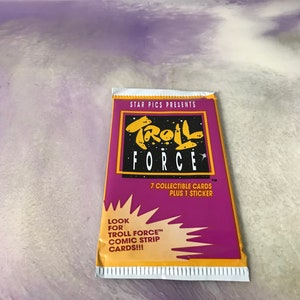 May include: A purple and yellow package of Troll Force trading cards. The package features the text "STAR PICS PRESENTS" and "TROLL FORCE" in a bold, stylized font. The package also includes the text "7 COLLECTIBLE CARDS PLUS 1 STICKER" and "LOOK FOR TROLL FORCE™ COMIC STRIP CARDS!!!".