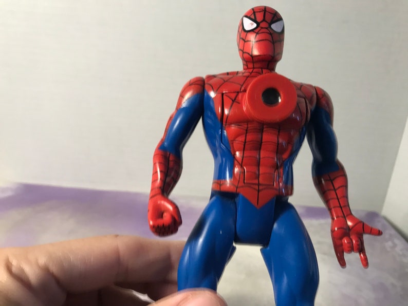 May include: A red and blue plastic action figure of Spider-Man. The figure has a web design on its chest and a black eye mask.