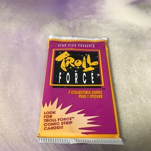 May include: A purple and yellow package for Troll Force collectible cards. The package features a cartoon troll with the text "Troll Force" and "7 collectible cards plus 1 sticker".