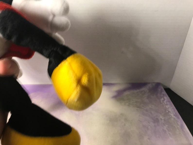 May include: A plush Mickey Mouse toy with red shorts, black shoes, and yellow gloves. The toy is made of soft, cuddly fabric and is perfect for cuddling.