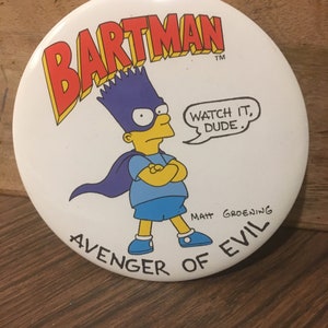 May include: A white button featuring a cartoon image of Bart Simpson dressed as a superhero. The button reads "Bartman" in red letters, "Avenger of Evil" in black letters, and "Watch it, Dude." in a speech bubble. The button is signed "Matt Groening" in the bottom right corner.