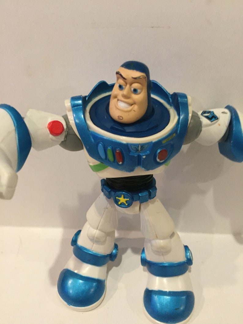 Pu&ograve; includere: Una action figure di Buzz Lightyear blu e bianca con una stella sulla cintura. La figura ha una testa rotante ed &egrave; in posizione eretta.