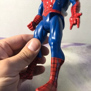 May include: A red and blue plastic action figure of Spider-Man. The figure has a detailed design with a web pattern on the suit and a red spider logo on the chest.