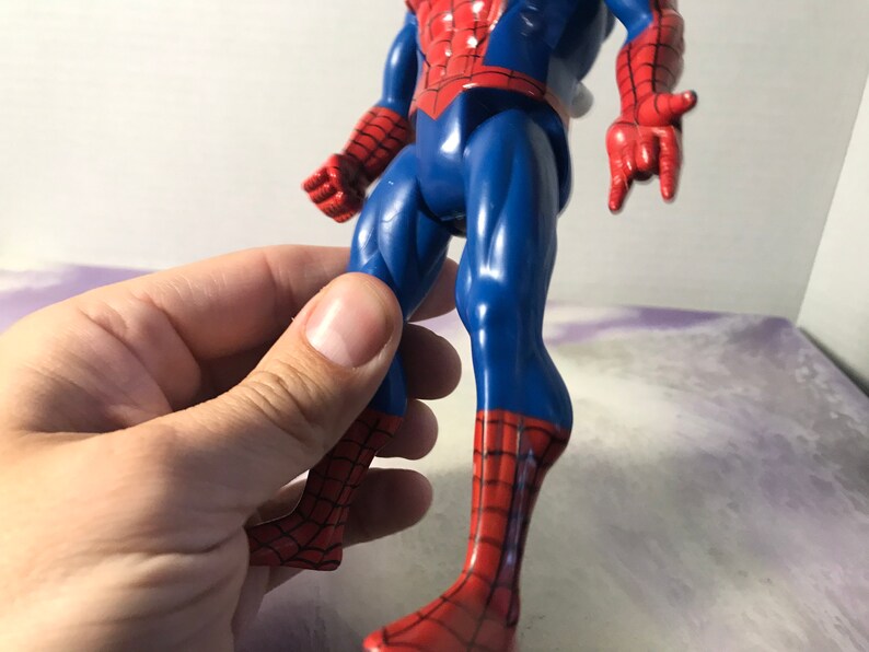 May include: A red and blue plastic action figure of Spider-Man. The figure has a detailed design with a web pattern on the suit and a red spider logo on the chest.