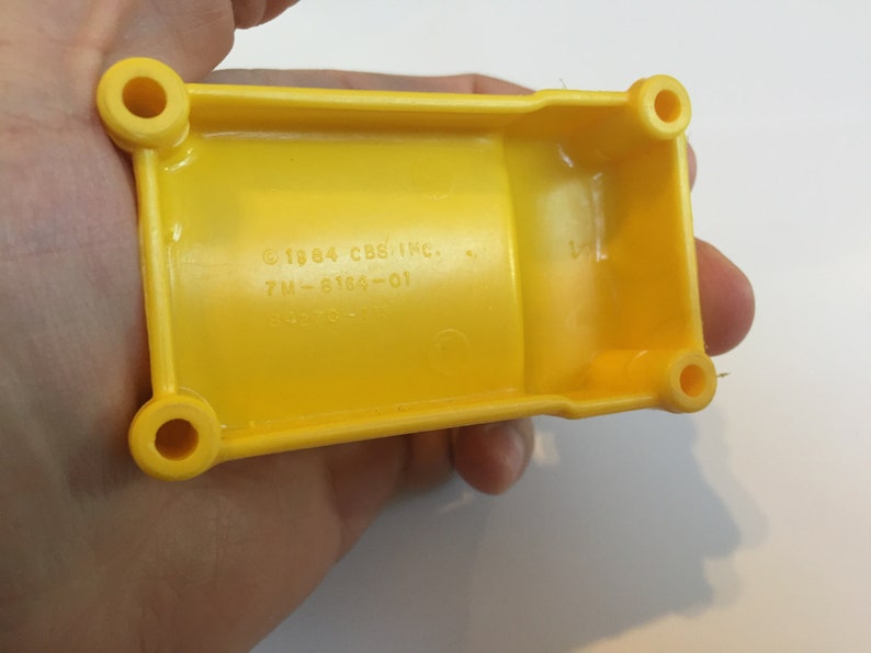May include: Yellow plastic toy truck with a copyright date of 1984 and the text "CBS INC. 7M-6164-01".