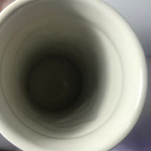 K&ouml;nnte beinhalten: Wei&szlig;e Keramiktasse mit glatter, gl&auml;nzender Oberfl&auml;che. Die Innenseite der Tasse ist leer.