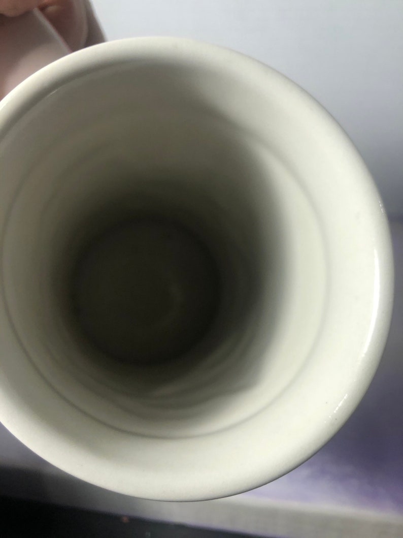 K&ouml;nnte beinhalten: Wei&szlig;e Keramiktasse mit glatter, gl&auml;nzender Oberfl&auml;che. Die Innenseite der Tasse ist leer.