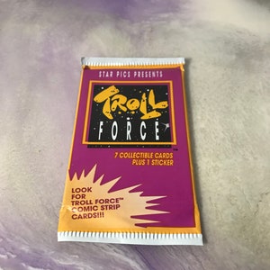 May include: A purple and yellow package of Troll Force trading cards. The package features a cartoon troll with the words "Troll Force" and "7 collectible cards plus 1 sticker".