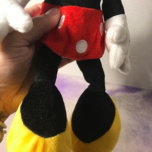 May include: A plush Mickey Mouse toy with black fur, red shorts with white polka dots, and yellow shoes.
