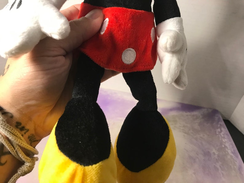 May include: A plush Mickey Mouse toy with black fur, red shorts with white polka dots, and yellow shoes.