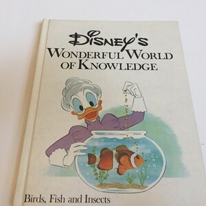 May include: A vintage children's book titled "Disney's Wonderful World of Knowledge: Birds, Fish and Insects". The cover features a cartoon illustration of a female duck character feeding a clownfish in a fishbowl.